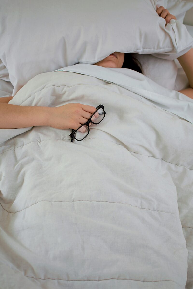 A closer look into your overall health's role in memory loss with person holding glasses sleeping