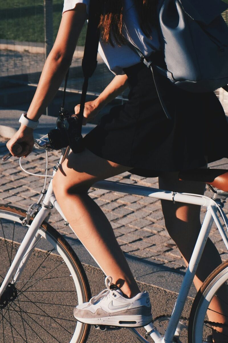 Touring goals: why bar end shifters are a must-have for your next adventure with woman riding a bike next to a brick path