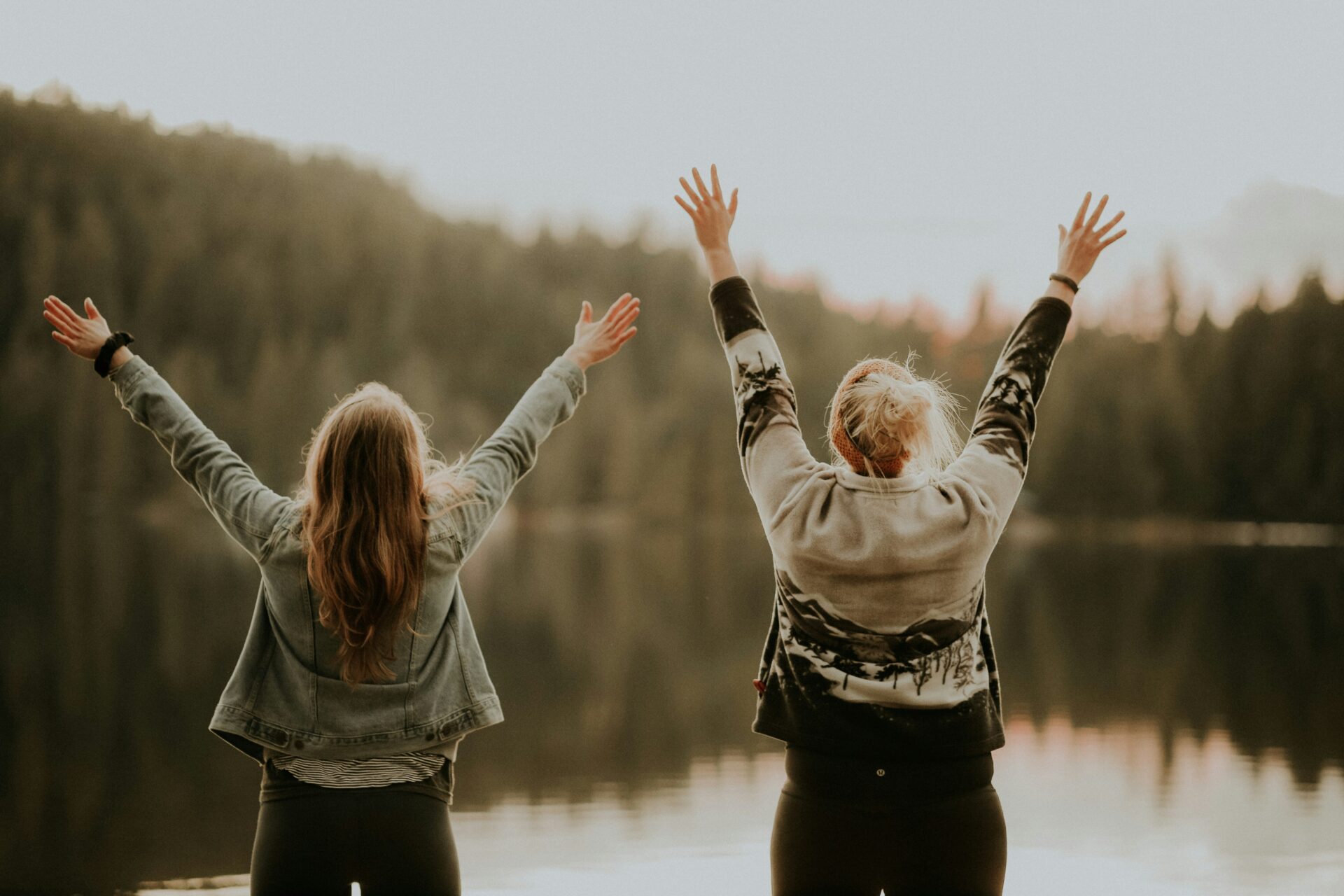 Smart & simple: let emotional intelligence help you overcome life challenges with woman in front of a lake with hands up in the air