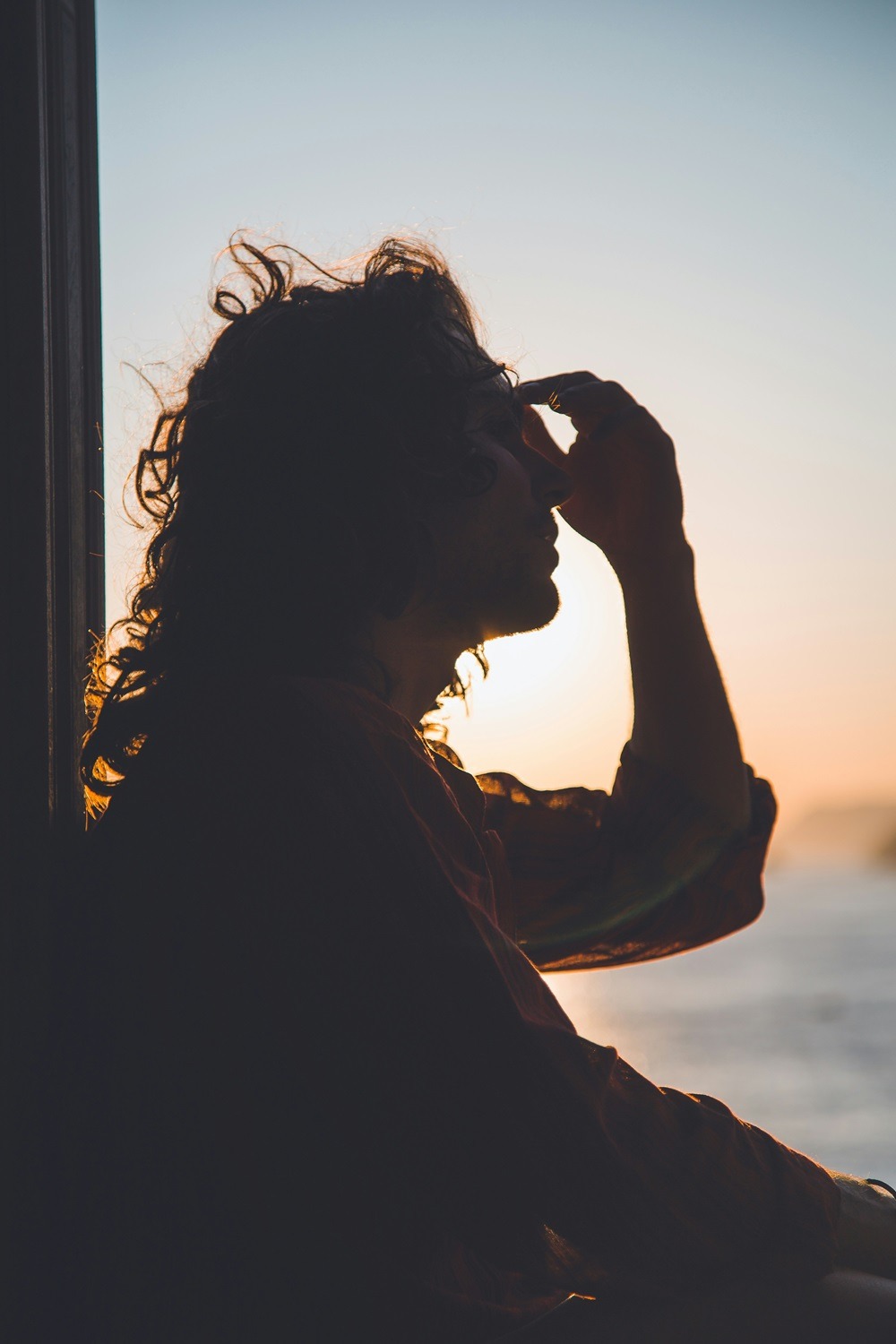 Woman experiencing brain fog sits by window with hands on head, illustrating how diet and brain health affects mental clarity and focus
