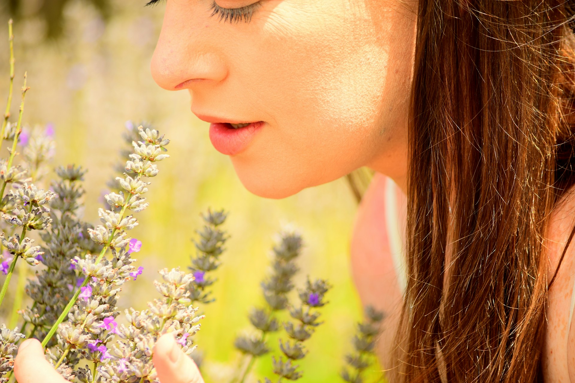 Woman connecting with nature, holding purple flowers close to her face, promoting relaxation and mindfulness